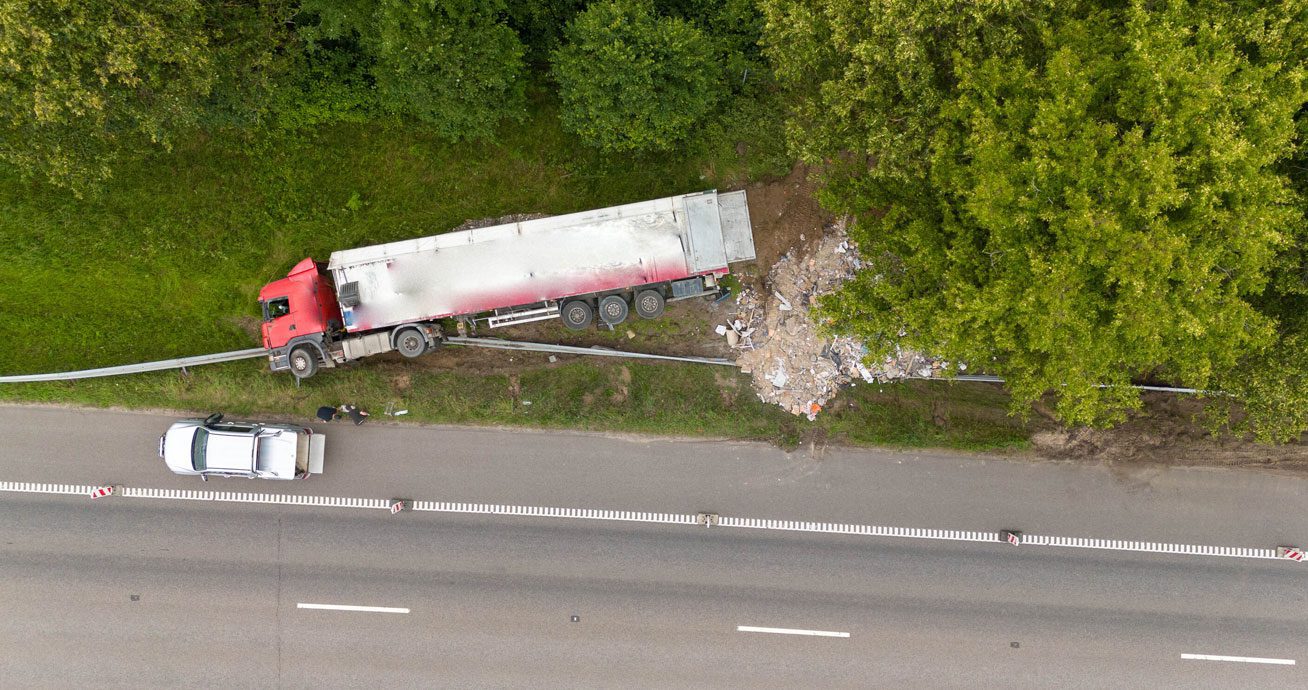Aerial-view-of-truck-off-road-with-debris-near-tree-line
