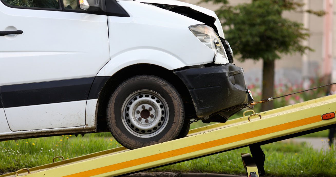 Close-up-of-damaged-car-being-lifted-onto-tow-truck-platform
