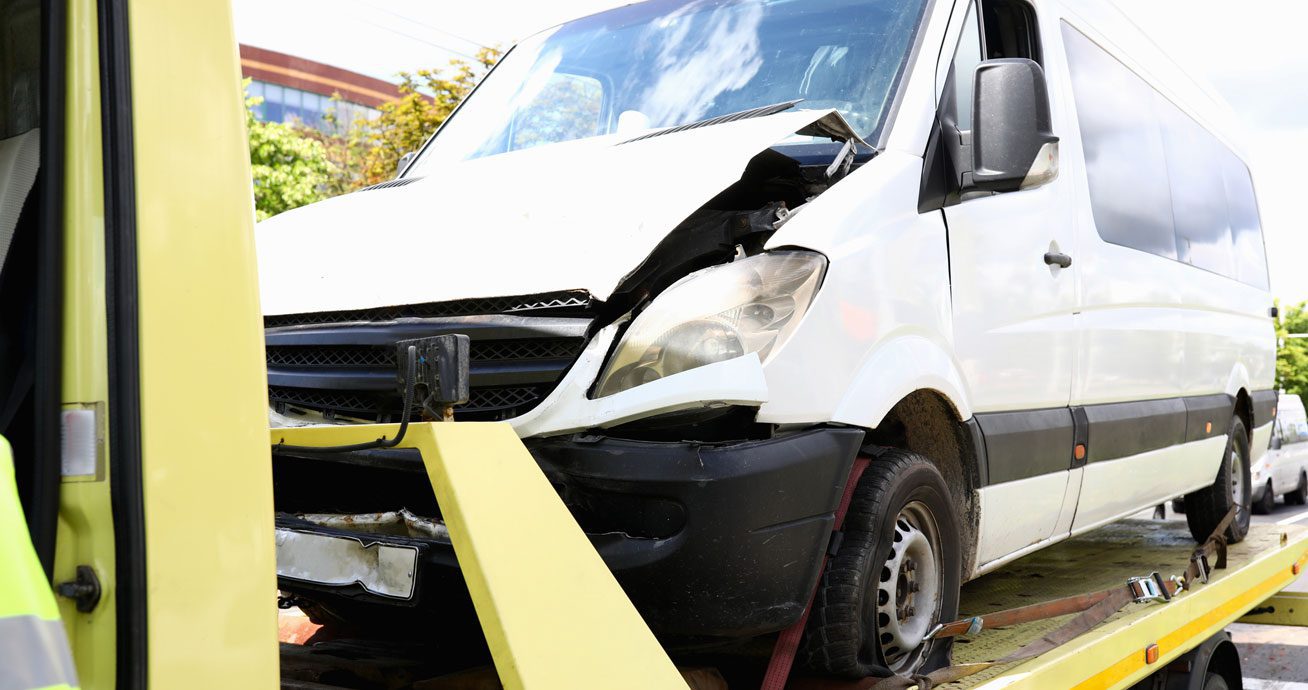 Damaged-white-van-loaded-onto-flatbed-tow-truck