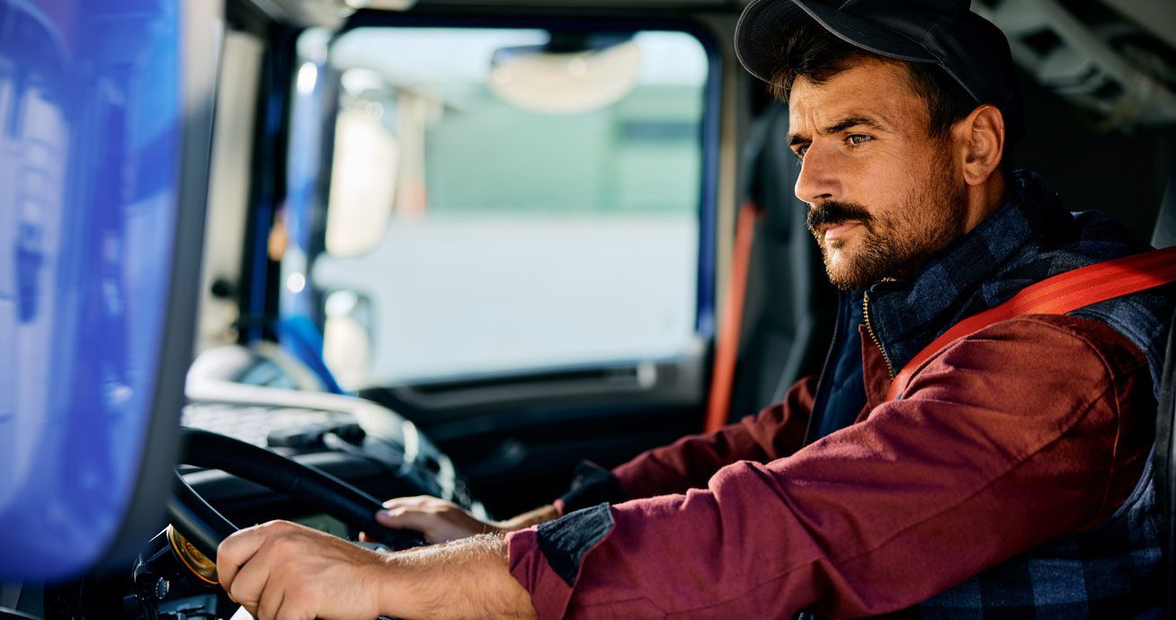 Driver-holding-steering-wheel-inside-truck-cab-looking-ahead