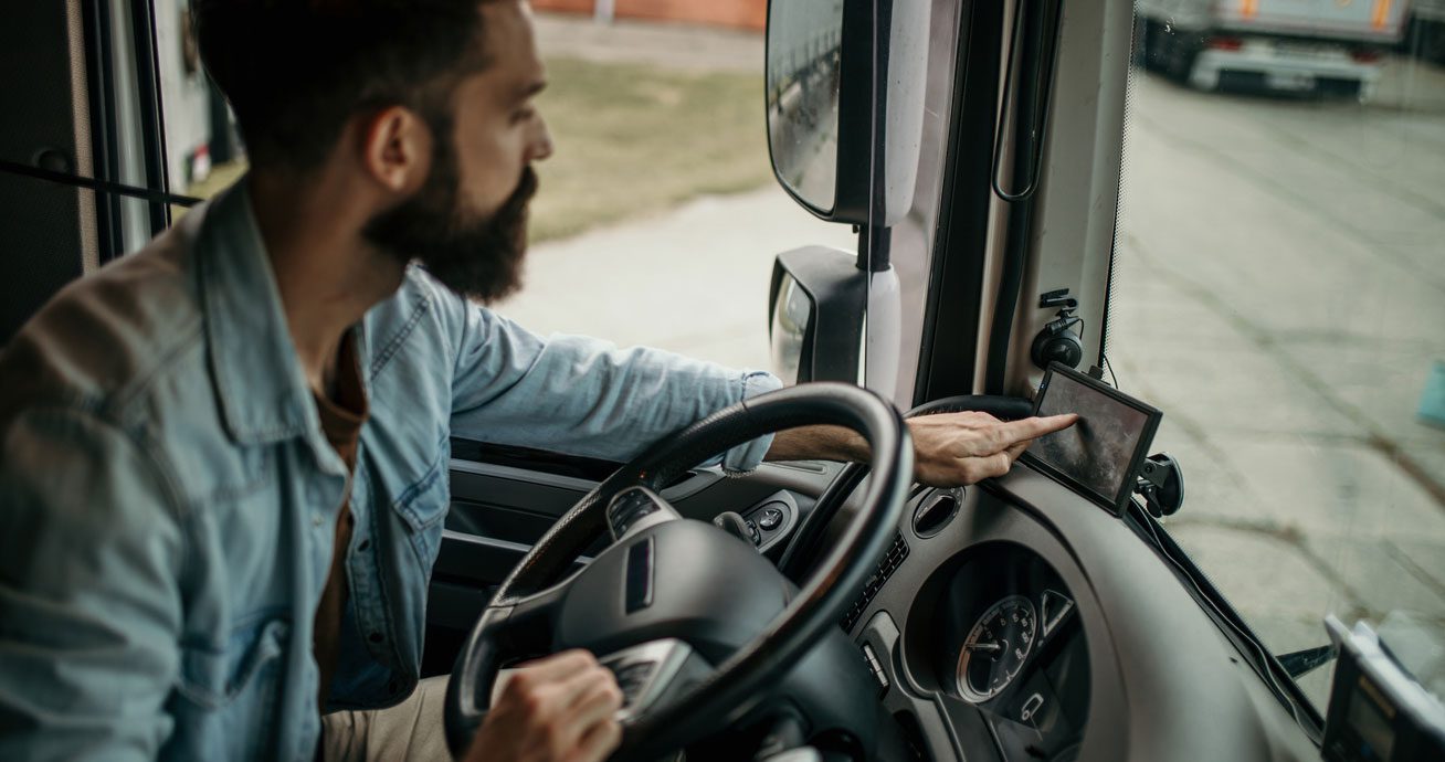 Driver-reaching-toward-dashboard-screen-inside-truck-cab