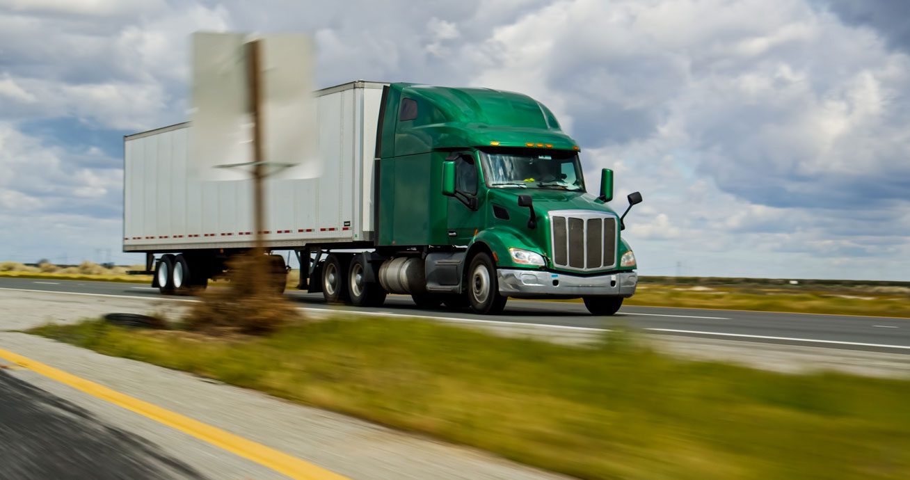 Green-semi-truck-pulling-trailer-on-highway-with-motion-blur