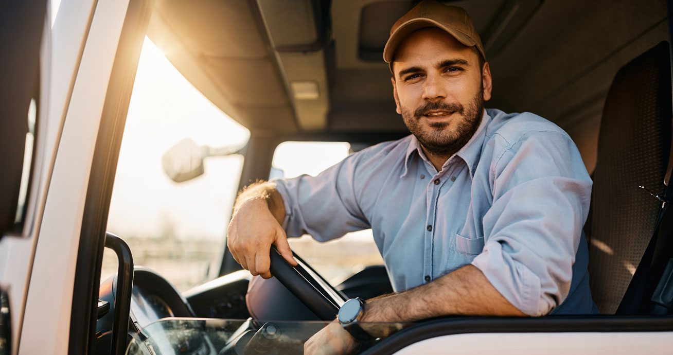 Man-sitting-in-truck-cab-with-hand-on-steering-wheel