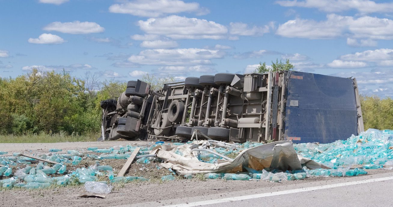 Overturned-truck-on-roadside-with-scattered-cargo-and-debris