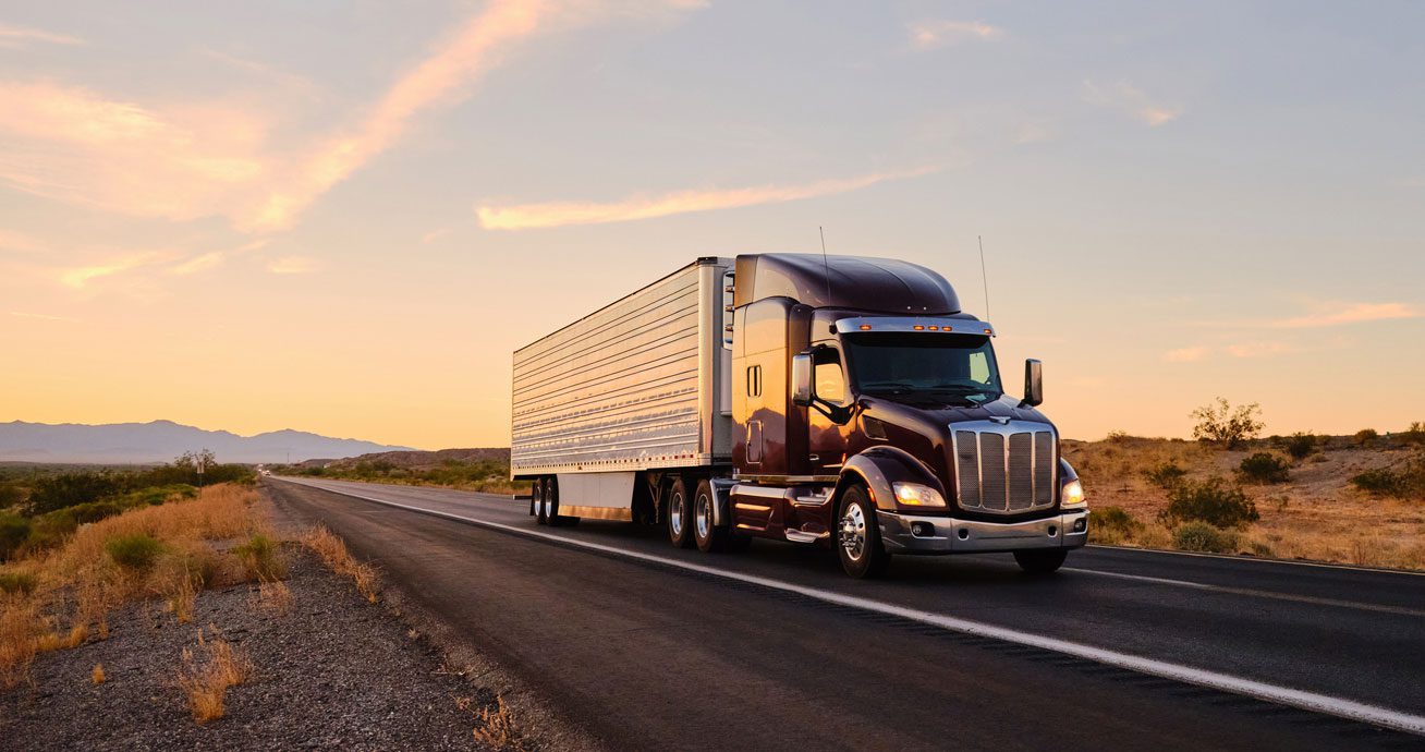Semi-truck-driving-along-highway-with-open-landscape-on-both-sides