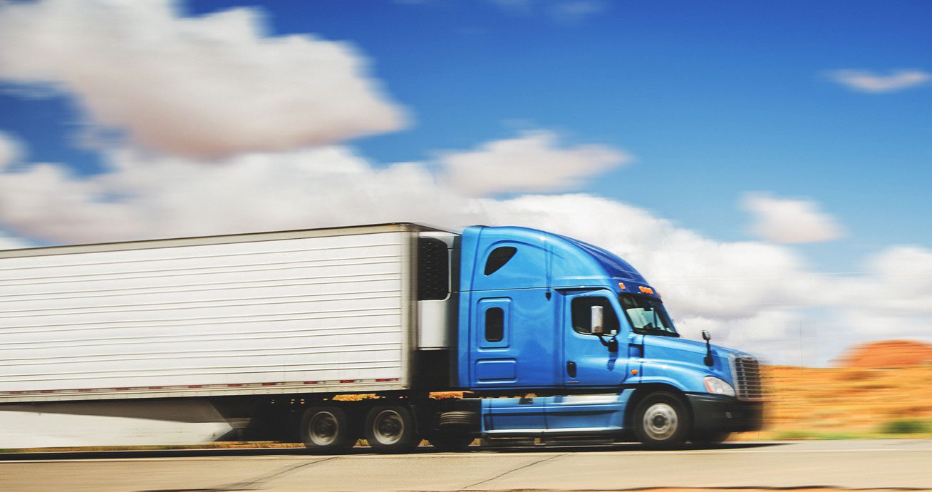 Semi-truck-driving-on-two-lane-road-with-desert-landscape