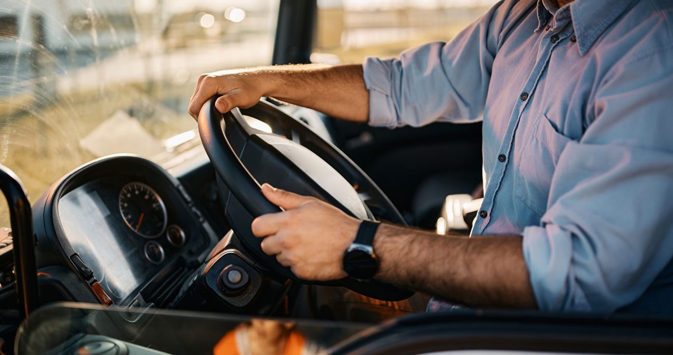 Truck-driver-holding-steering-wheel-inside-cab