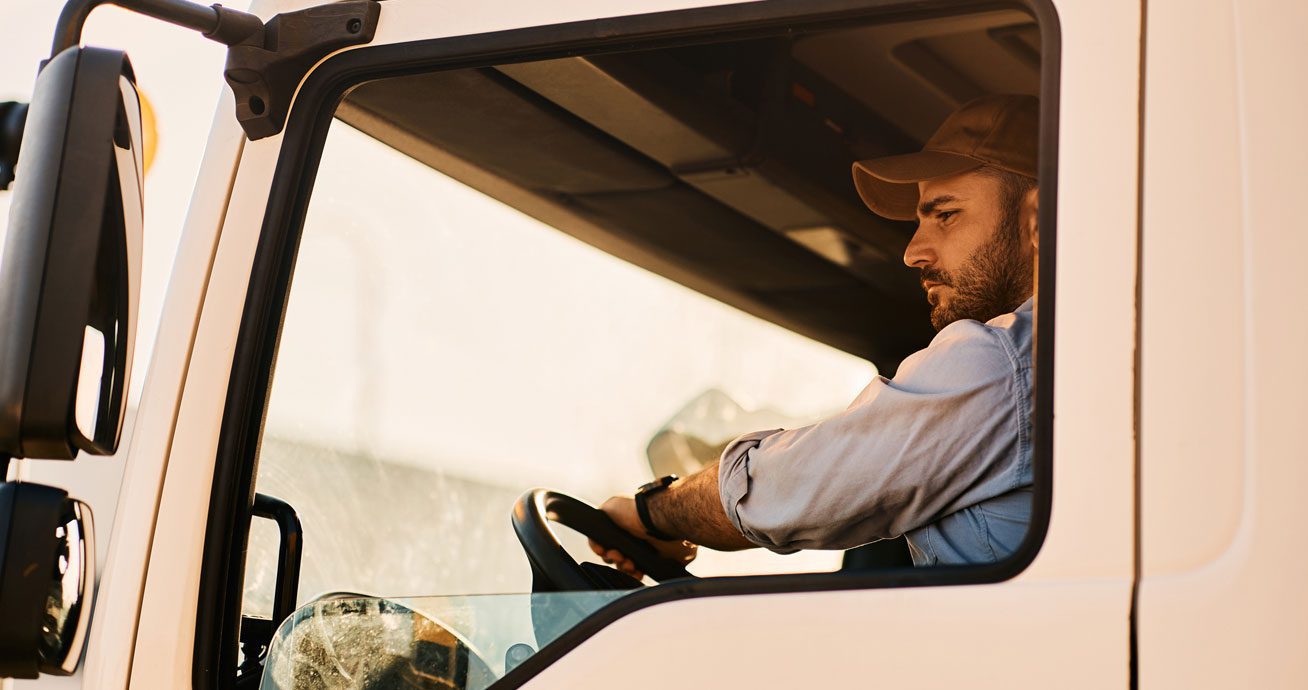 Truck-driver-looking-into-side-mirror-while-reversing-vehicle