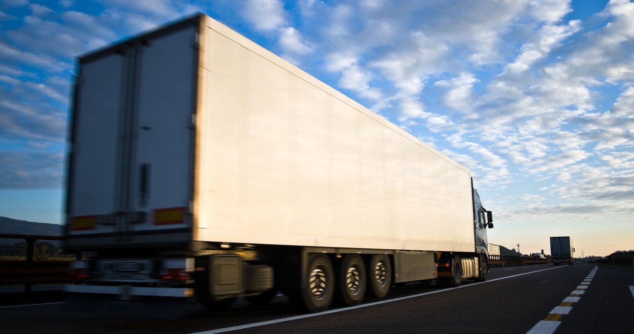 Truck-driving-fast-on-highway-with-motion-blur-and-cloudy-sky