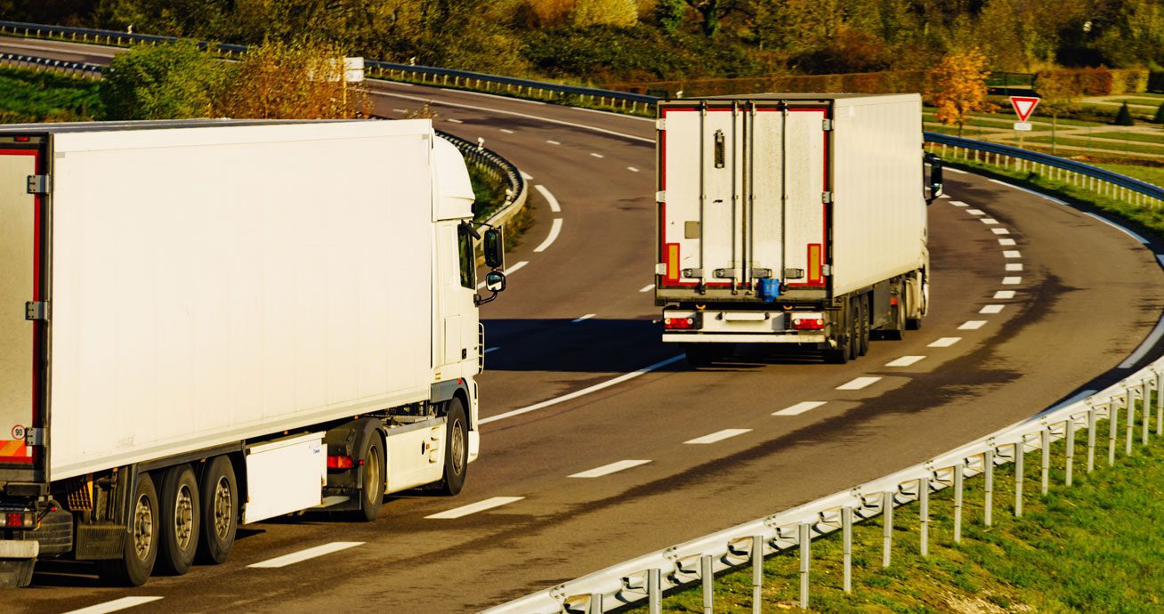 Two-trucks-driving-on-curved-highway-road