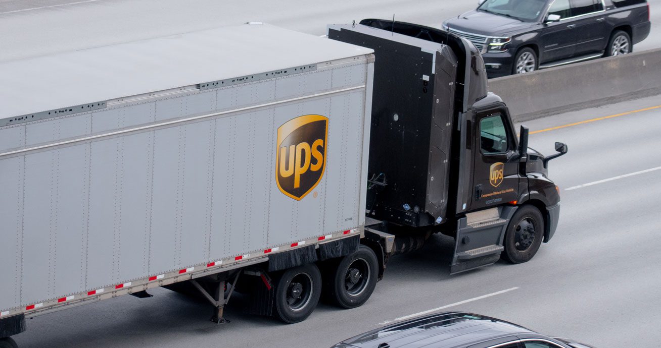 UPS-delivery-truck-driving-on-highway-with-surrounding-traffic