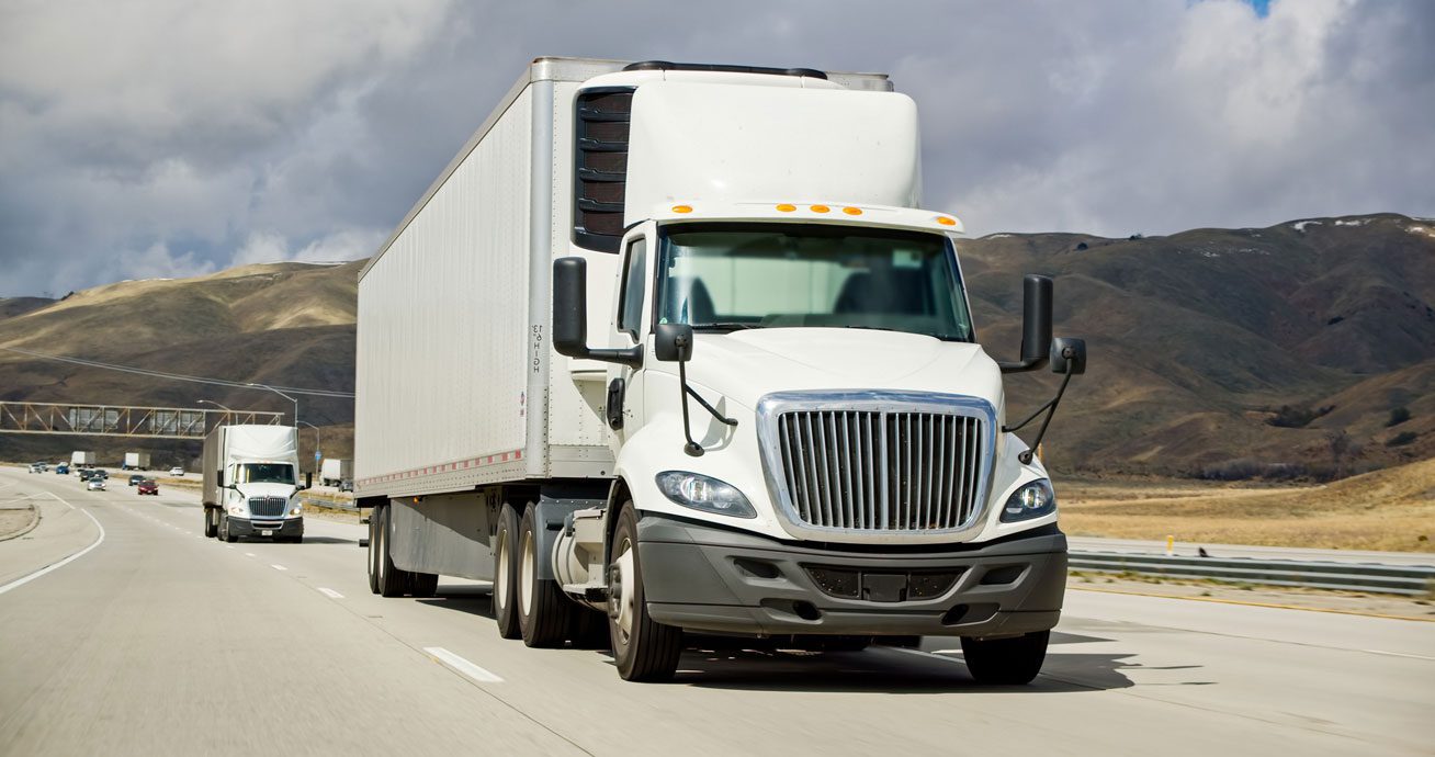 White-semi-truck-driving-on-highway-with-another-truck-behind