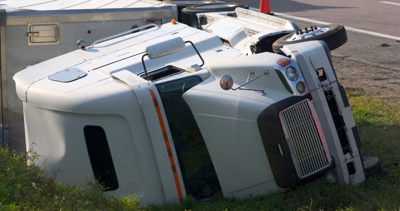 White-semi-truck-overturned-on-roadside-near-traffic-cones