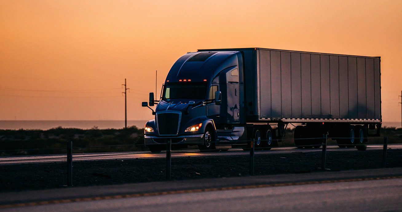 Blue-semi-truck-driving-on-wet-highway-under-storm-clouds