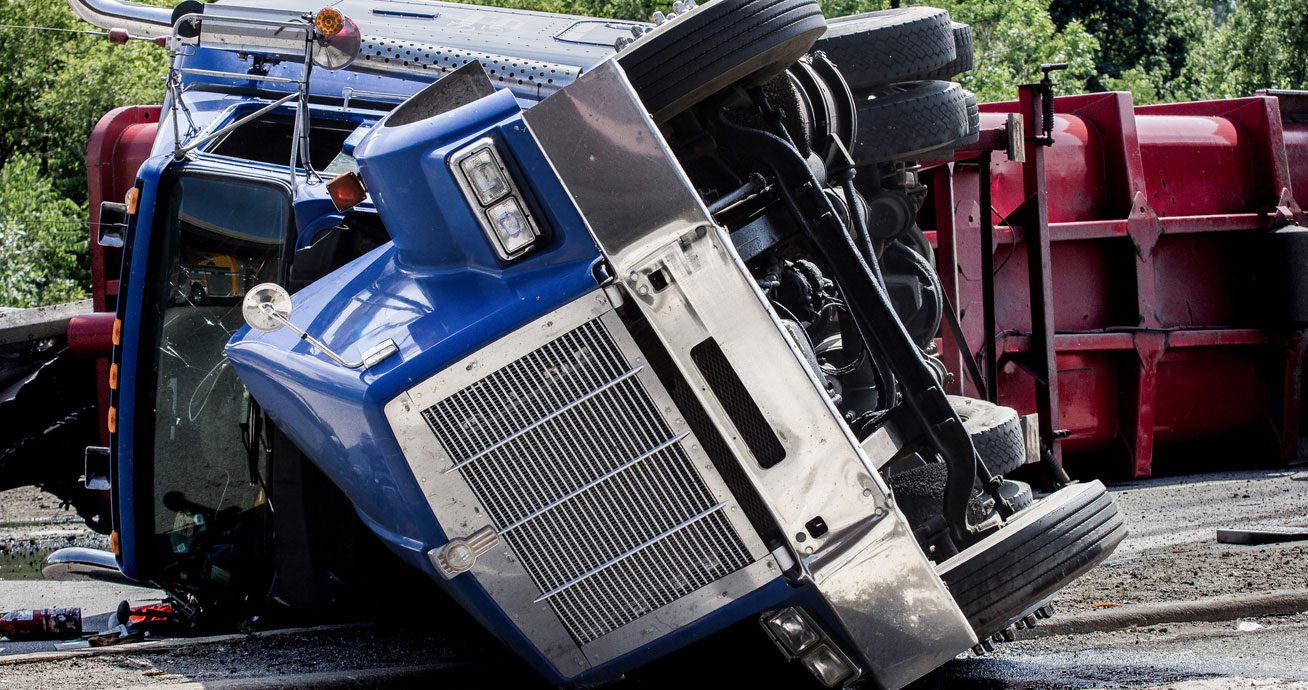 Blue-semi-truck-overturned-on-its-side-next-to-red-trailer