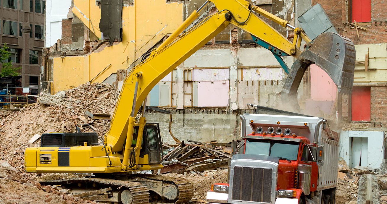 Front-loader-dumping-debris-into-dump-truck-at-demolition-site
