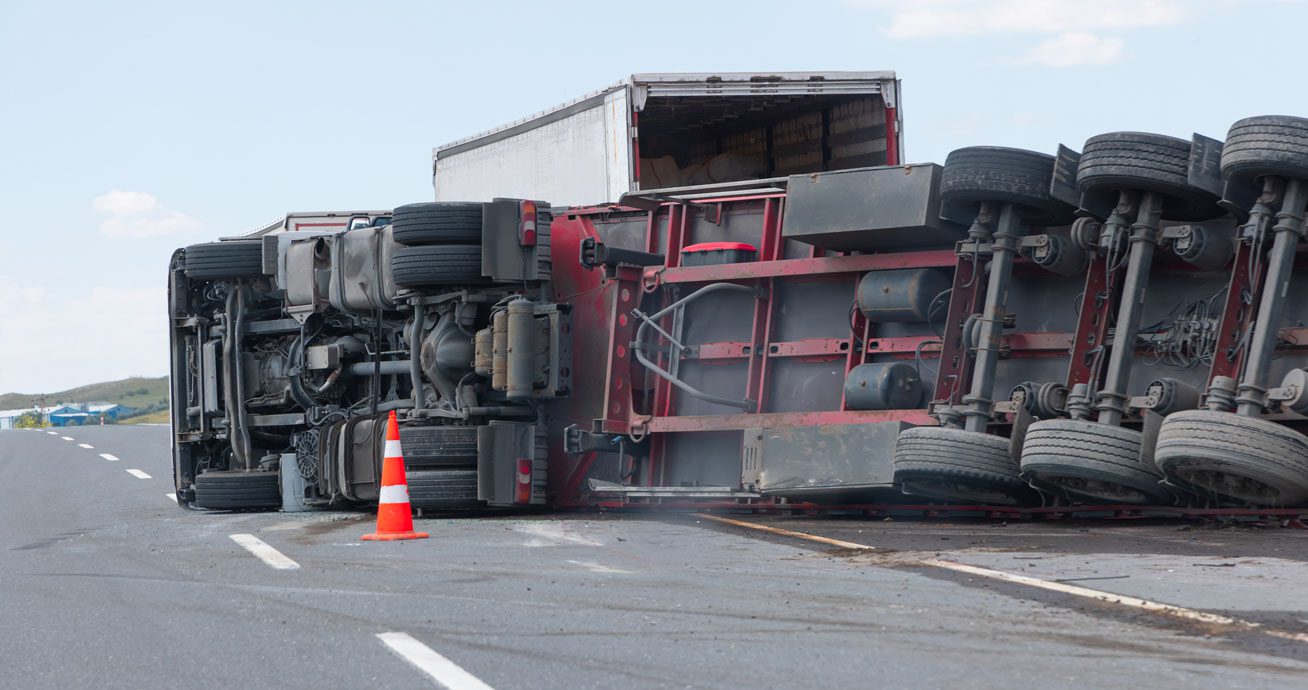 Overturned-semi-truck-blocking-lane-with-traffic-cone-nearby