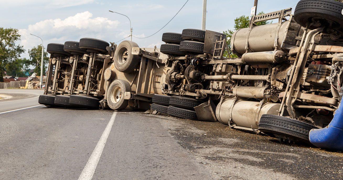 Overturned-semi-truck-lying-across-road-with-wheels-facing-upward