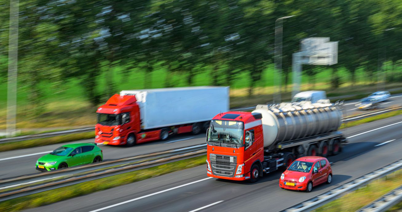 Red-trucks-and-cars-moving-along-multi-lane-highway