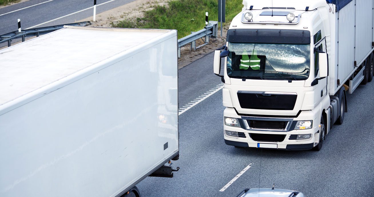 Truck-driving-on-highway-next-to-trailer-and-car