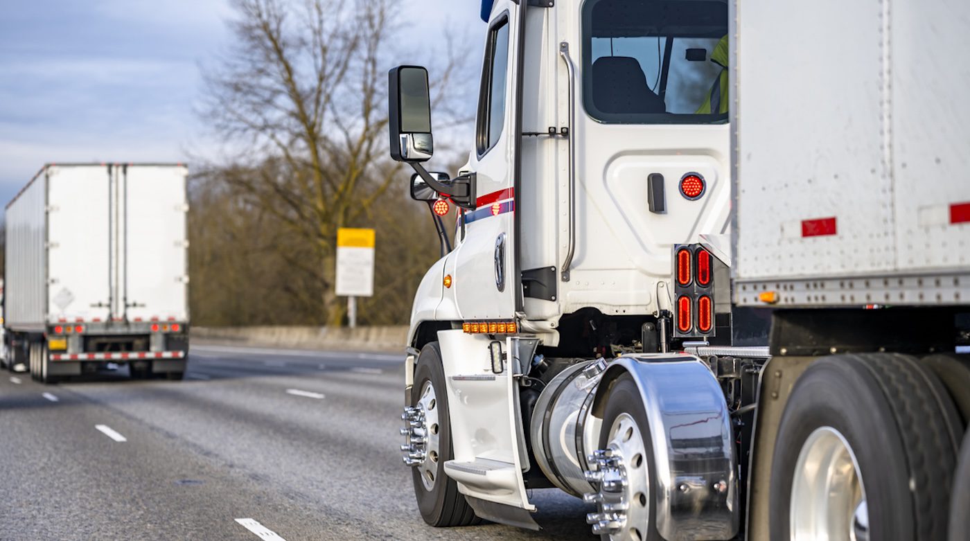 side rear view of a semi truck driving down the road