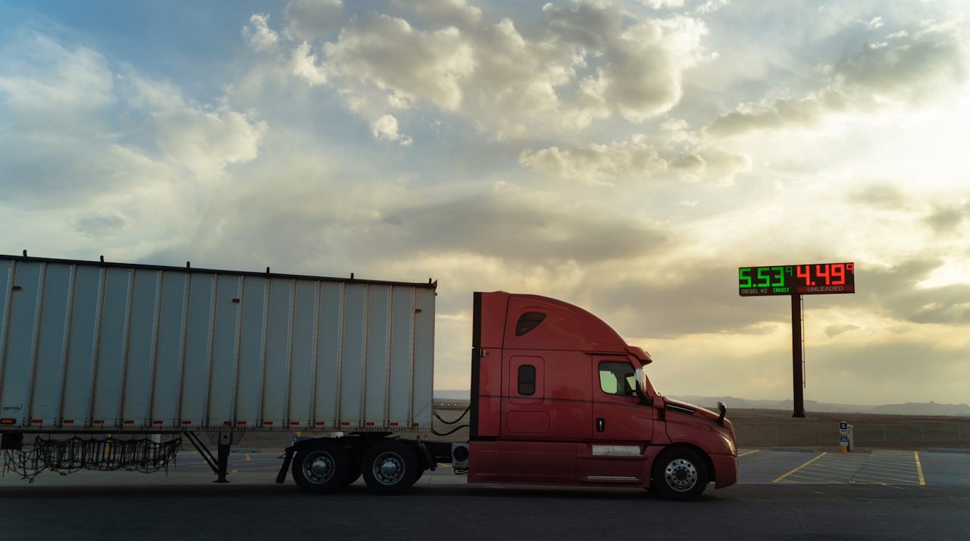 view at dusk of a semi truck near a gas station sign