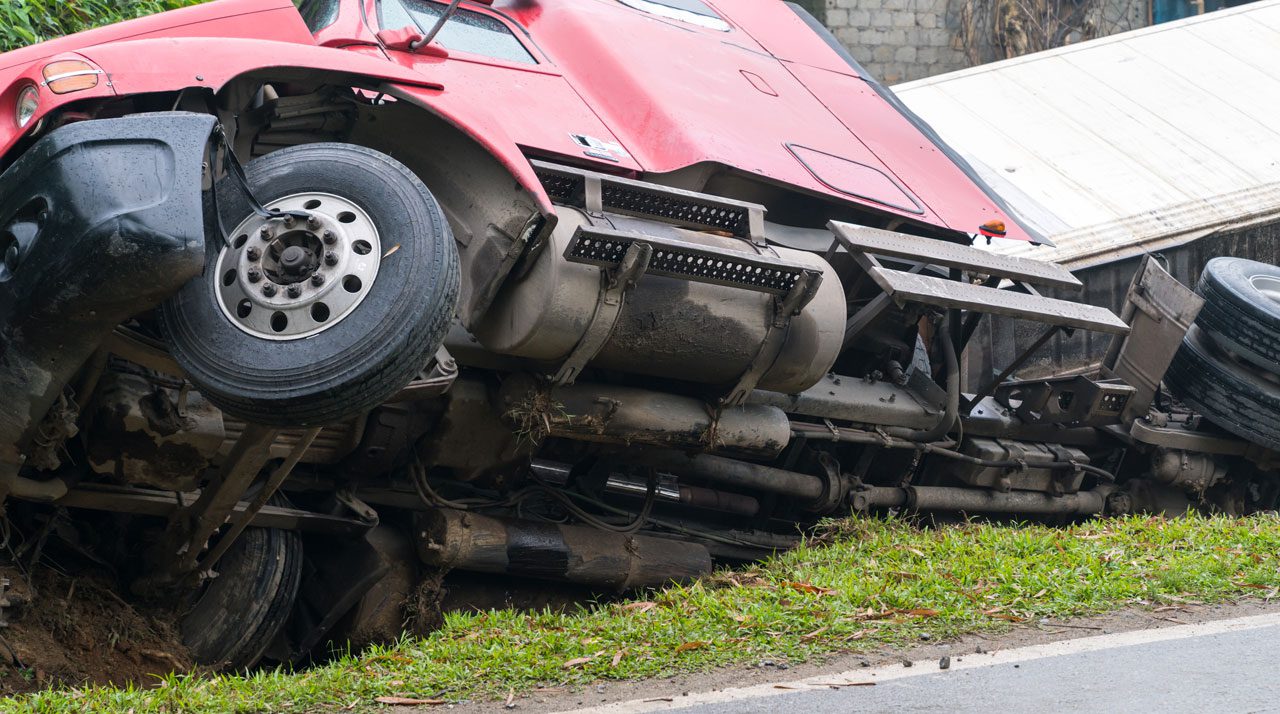 overturned-red-semi-truck-off-the-side-of-a-road