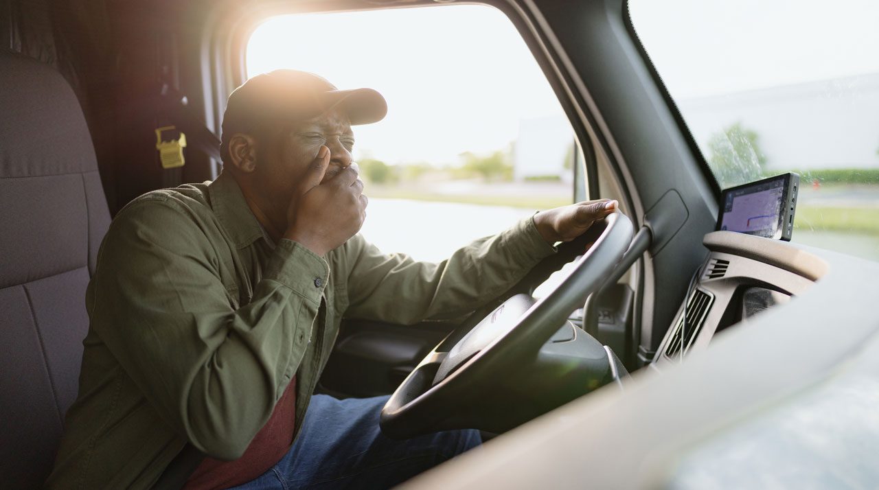 truck-driver-behind-the-wheel-with-sunlight-coming-through-the-windshield