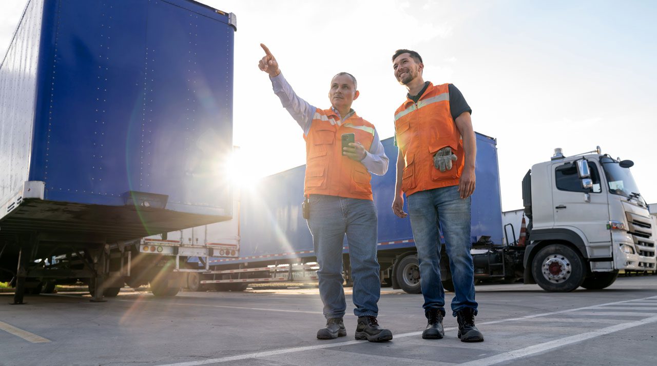 two-workers-in-safety-vests-inspecting-a-trailer-at-a-loading-yard