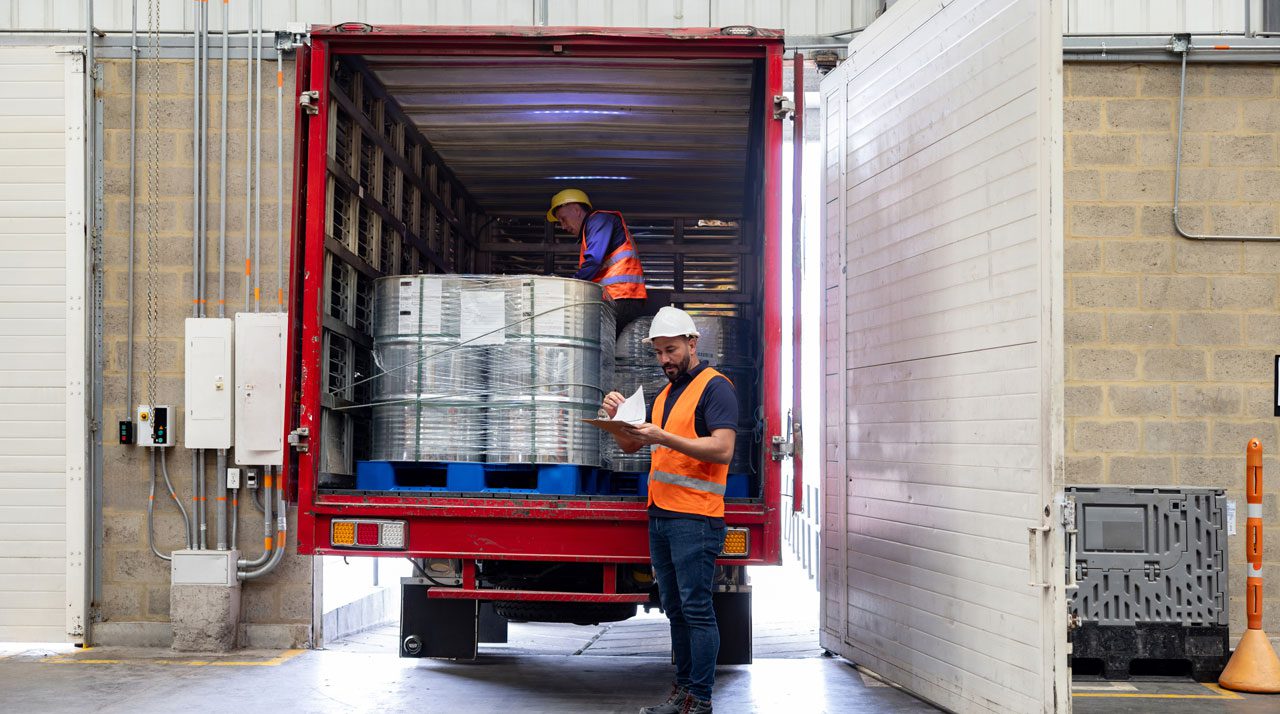 worker-loading-barrels-into-a-trailer-at-a-warehouse-dock